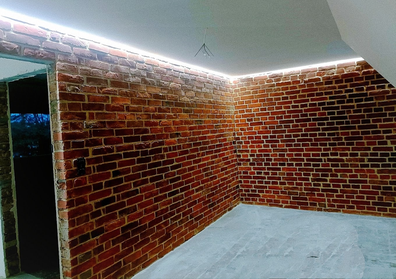 Pomieszczenie z ceglanymi ścianami i podświetlanym sufitem LED